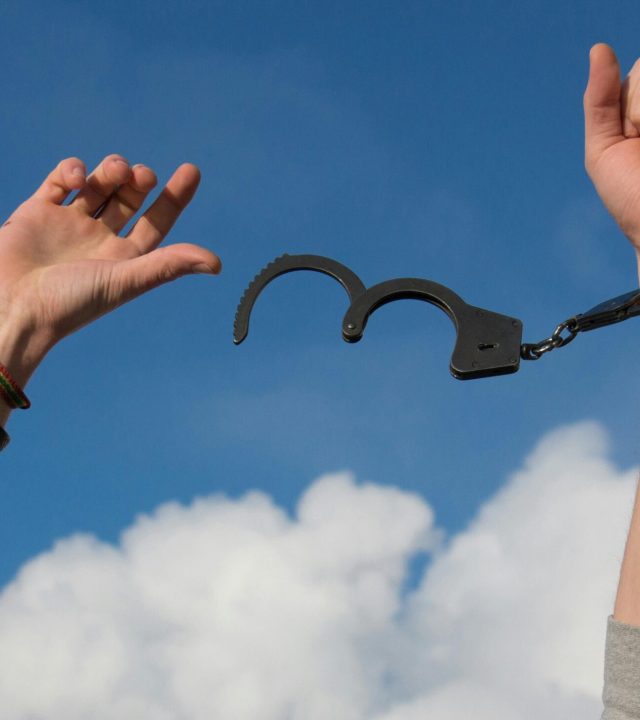 Symbolic image of freedom with open handcuffs against a bright blue sky.